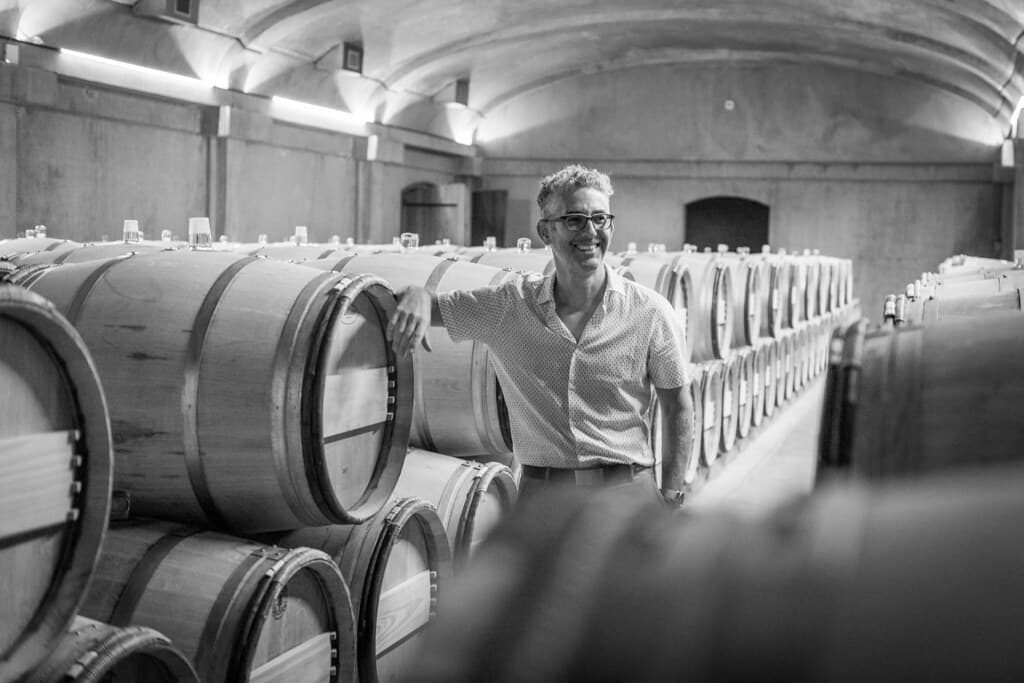 David Gluzman leaning on a barrel in a Bordeaux cellar