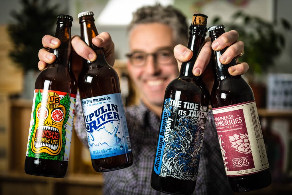 David Gluzman holding four craft beer bottles up to the camera