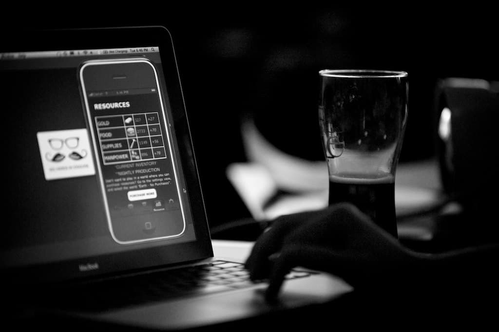 A laptop mid-demo, showing an iPhone app, beside a pint at DemoCamp Calgary