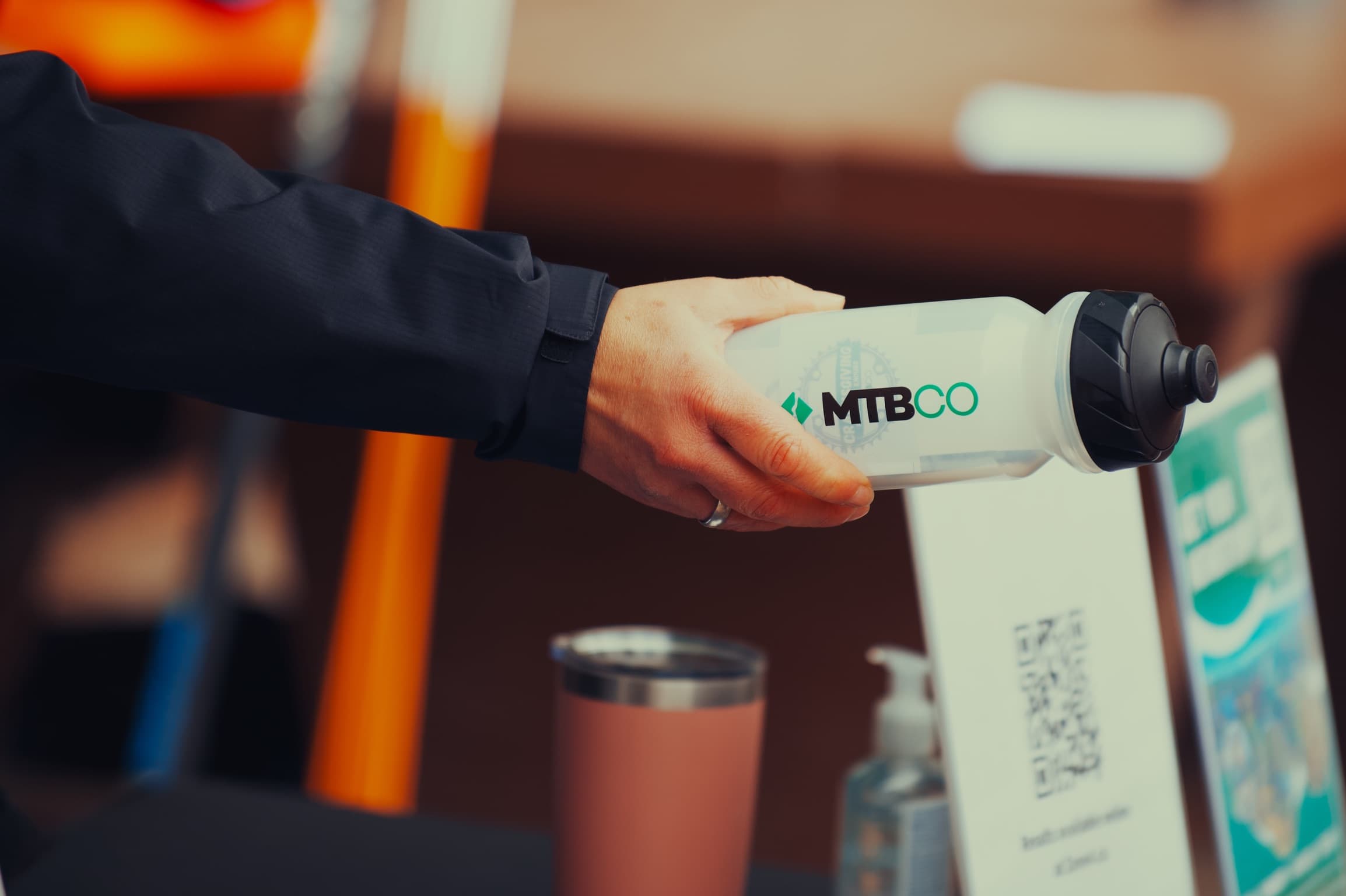 Hand offering an MTBCO branded water bottle