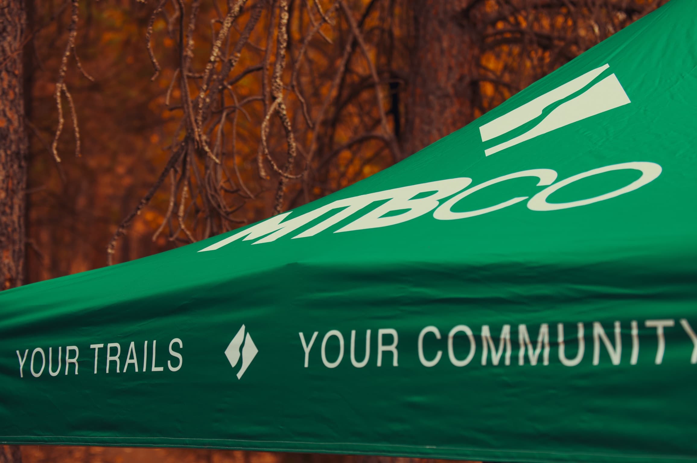 The trail society’s event tent in an autumn forest, printed with “your trails, your community”