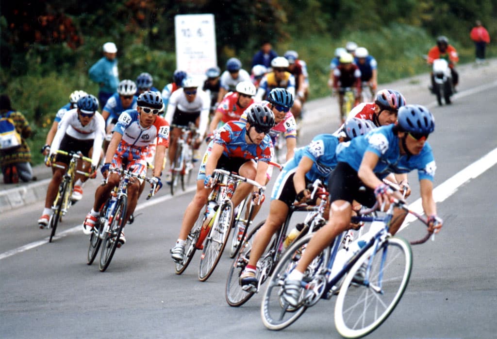 A pack of riders leaning into a corner at a road race in Japan