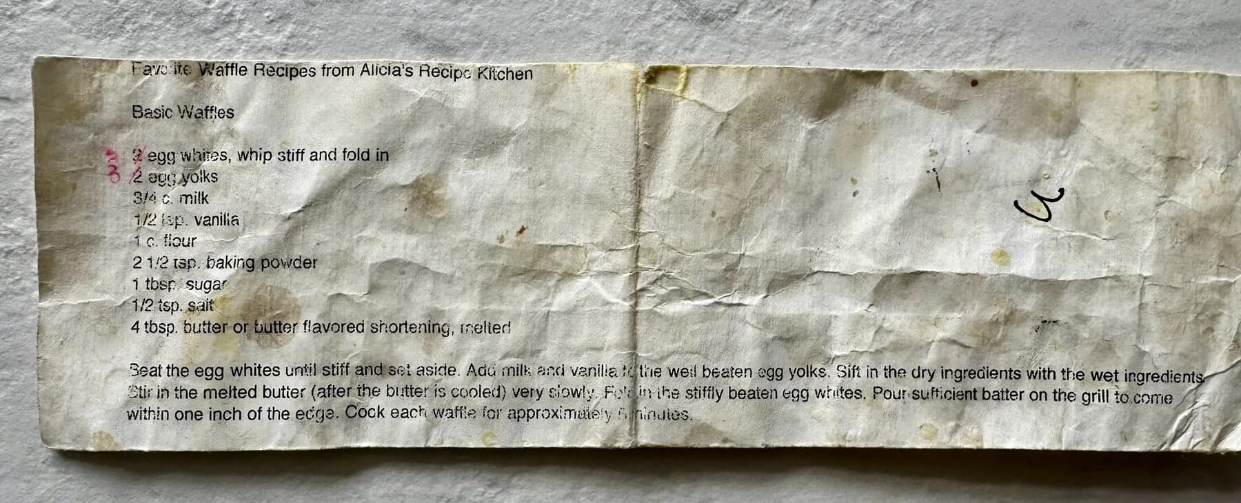 A printed waffle recipe card, folded and creased, with a handwritten correction over the egg count